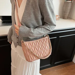 Détail du sac seau plissé rose clair avec chaîne dorée et finition en cuir texturé