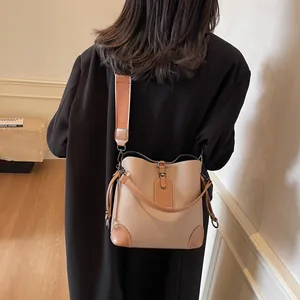 Détail du sac seau en cuir grainé kaki avec large bandoulière réglable sur modèle