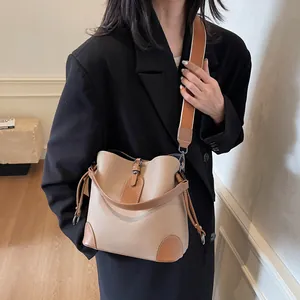 Détail du sac seau beige grainé avec finitions en cuir marron et large bandoulière en tissu