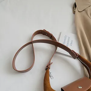 Detail of brown suede crossbody bag showing leather strap and silver buckle closure