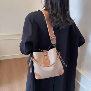Détail du sac seau beige avec bordure marron porté par un mannequin, vue de l'arrière