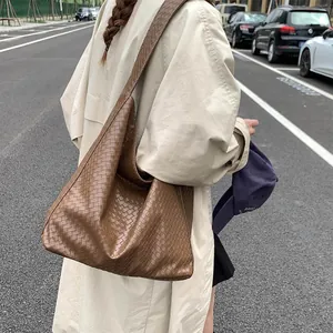 Detail of soft brown woven leather tote bag with Intrecciato pattern for winter fashion