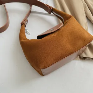 Close-up of caramel brown crescent bag with suede and leather textures on a table