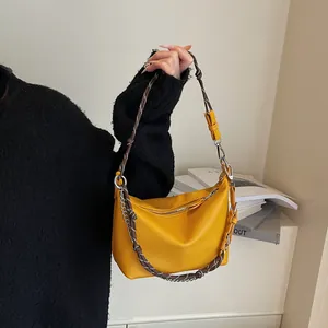 Close-up of bright yellow litchi grain leather bag with woven rope and chain strap