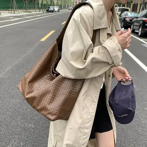 Detail of caramel brown woven leather tote bag texture and soft Hobo design in outdoor setting