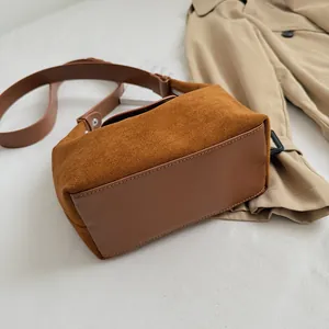 Detailed macro view of caramel suede and leather patchwork on this structured box bag
