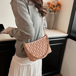 Détail du sac seau rose matelassé avec texture plissée et chaîne dorée élégante