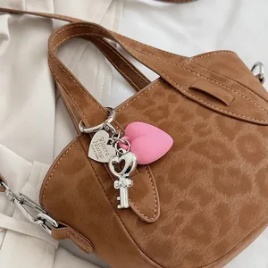 Dettaglio borsa leopardata con pendenti a cuore e ciondoli a chiave in argento lucido