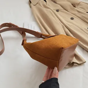Detail of brown leather and suede stitching on shoulder bag with adjustable strap