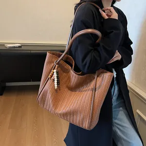 Detailed side view of brown woven leather tote bag with stylish wooden bead accessory