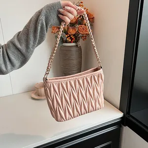 Sac seau rose plissé avec bandoulière chaîne dorée dans un cadre de vie élégant
