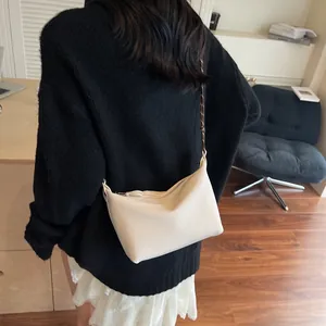 Close-up of beige lychee pattern leather texture on a minimalist crescent shoulder bag