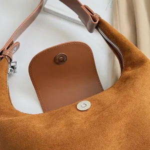 Detail of caramel suede hobo bag showing magnetic buckle and premium metal zipper closure
