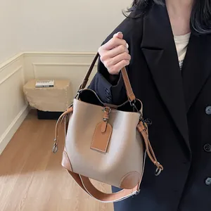 Gros plan sur la texture grainée du sac seau bicolore avec large bandoulière réglable