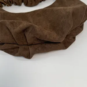 Detail of the soft dark brown suede texture and pleated drawstring design on the tote bag