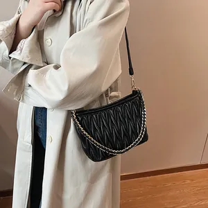 Détail du sac seau plissé noir avec cuir texturé et bandoulière en chaîne dorée chic
