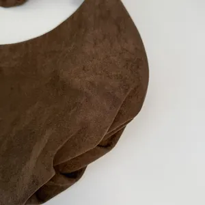 Close-up of high-quality dark brown suede texture and pleated design on shoulder bag