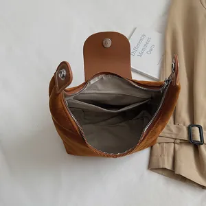 Detail view of the brown suede handbag interior with herringbone lining and pockets