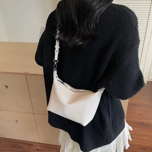Detail of white litchi pattern leather bag with silver zipper and slim strap