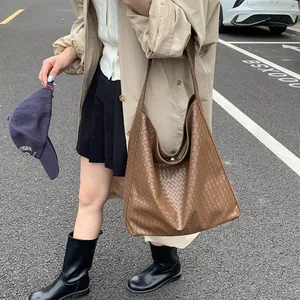 Detailed view of brown woven PU leather tote bag in a stylish street fashion setting
