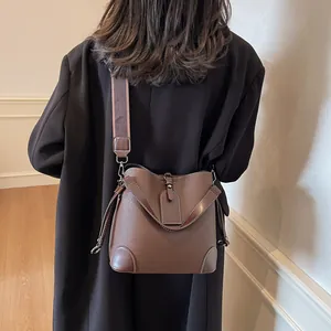 Détail du sac seau en cuir marron foncé avec coins renforcés et large bandoulière