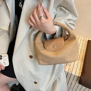 Close-up of camel suede handbag with leather flap and metallic snap closure