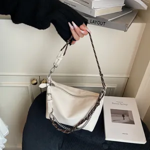 Detail of cream textured leather bag with woven rope strap and silver chain hardware