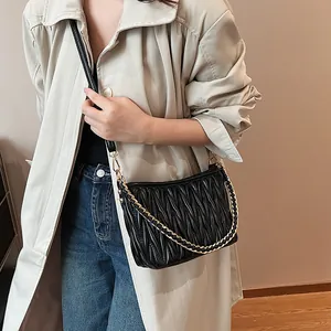 Détail du sac seau noir matelassé avec chaîne en métal porté par un mannequin femme