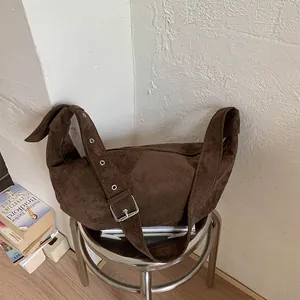 Close-up of dark brown suede dumpling bag with adjustable strap and silver metal buckle