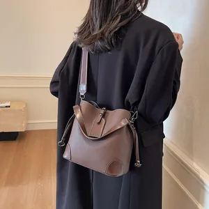 Sac seau en cuir grainé marron porté par un mannequin pour illustrer la taille