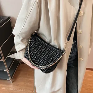 Détail du sac seau noir en similicuir plissé avec chaîne dorée et bandoulière réglable