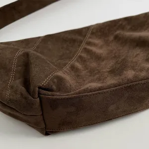 Close-up of the stitching details and matte suede texture on the dark brown crossbody bag