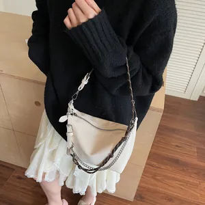 Detail of off-white lychee leather hobo bag with woven strap and silver metal chain