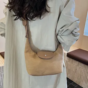 Close-up of a vintage khaki suede hobo bag with brown leather strap and crescent shape