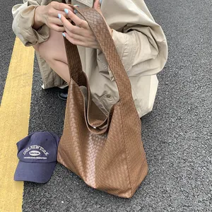 Detail of a brown woven leather hobo bag showcasing intricate cross-knit texture