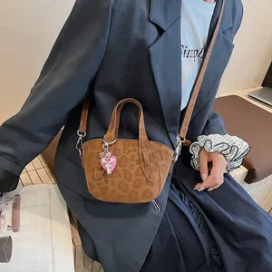 Dettaglio di una mini borsa leopardata con ciondolo a cuore rosa e tracolla rimovibile