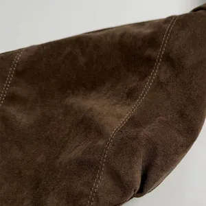 Macro shot of dark brown matte suede texture with precision double-row stitching detail