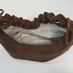 Close-up of brown suede bag with fishbone pattern lining and silver zipper detail