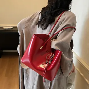 Borsa tote in pelle cerata rossa con ciondolo a cuore indossata da una modella elegante