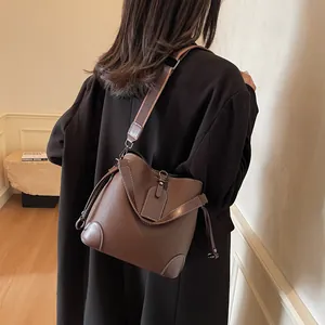Vue latérale détaillée du sac seau en cuir marron foncé avec surpiqûres blanches