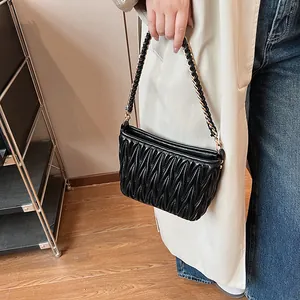 Détail du sac seau matelassé noir avec poignée en cuir tressé et chaîne dorée