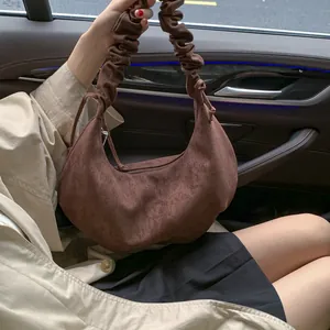 Detail of dark brown suede crescent bag with fashionable ruched shoulder strap detail