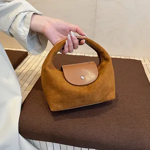 Detail of caramel suede and smooth leather stitching with silver metal buckle on bag