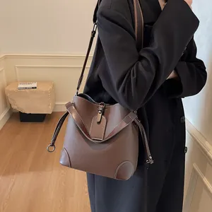 Détail d'un sac seau en cuir grainé marron avec surpiqûres blanches et bandoulière