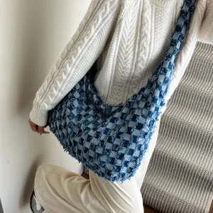 Detailed view of checkered denim hobo bag featuring frayed edges and a wide shoulder strap