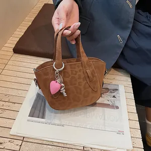 Dettaglio mini borsa a secchiello leopardata con ciondolo a cuore rosa e chiave