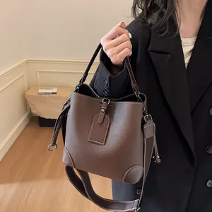 Détail du sac seau en cuir marron foncé avec surpiqûres blanches et large bandoulière