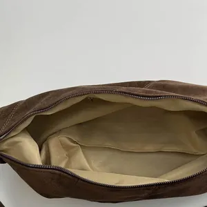 Top view of spacious interior of dark brown suede bag with beige lining and metal zipper