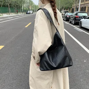 Close-up of a black woven tote bag showing the detailed texture on a woman's shoulder