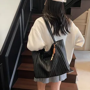 Detail of black woven PU leather tote bag with colorful beaded tassel charm decoration